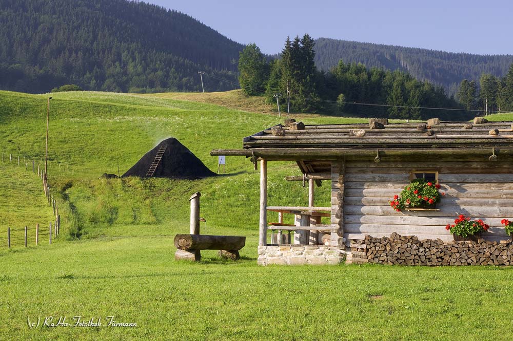 die Hütte der Köhler in Neukirchen in der Gemeinde Teisendorf mit dem Kohlenmeiler im Hintergrund, Berchtesgadener Land, Oberbayern, Deutschland
