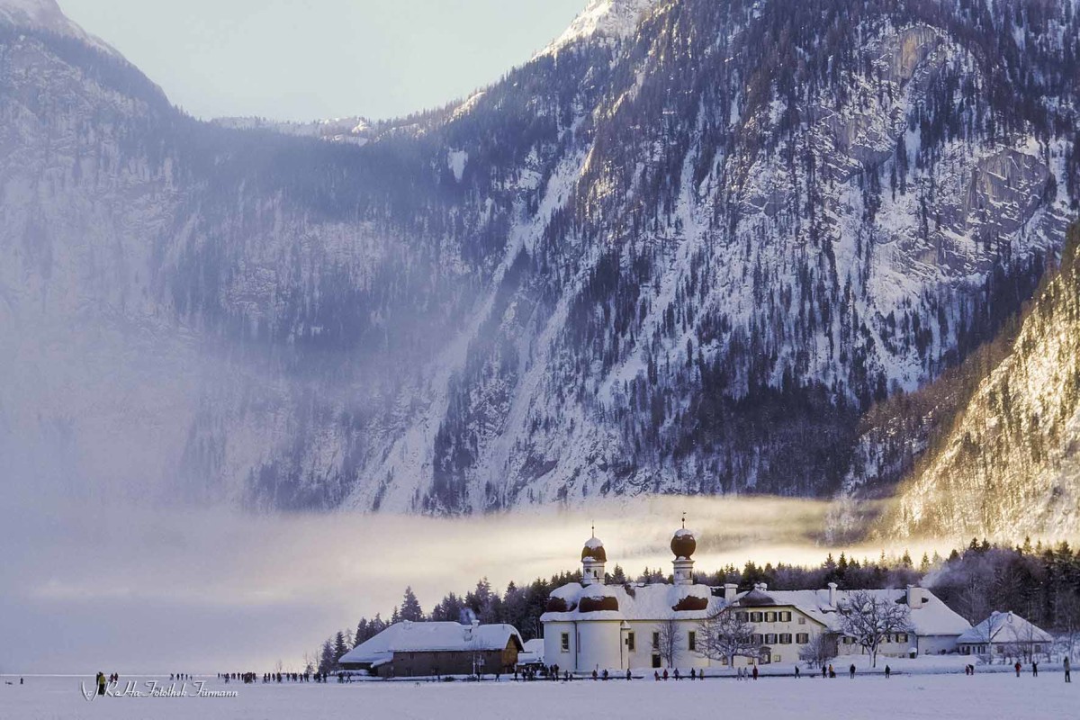 der zugefrorenen Königsee, tiefverschneit, mit St. Bartholomä im Hintergrund in der Morgensonne, ein sehr seltenes Naturschauspiel im Berchtesgadenre Land, Bayern