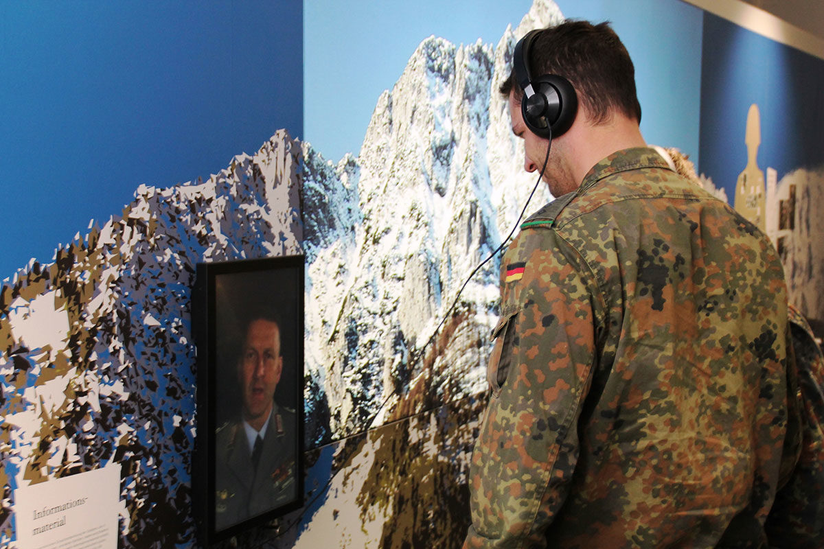 Ein Soldat der Gebirgsjägerbrigade hört sich einen Interviewbeitrag vor der Fotokulisse des Hochstaufens an
