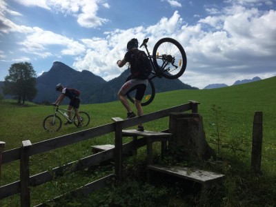 Mountainbiker trägt Rad über Zaun